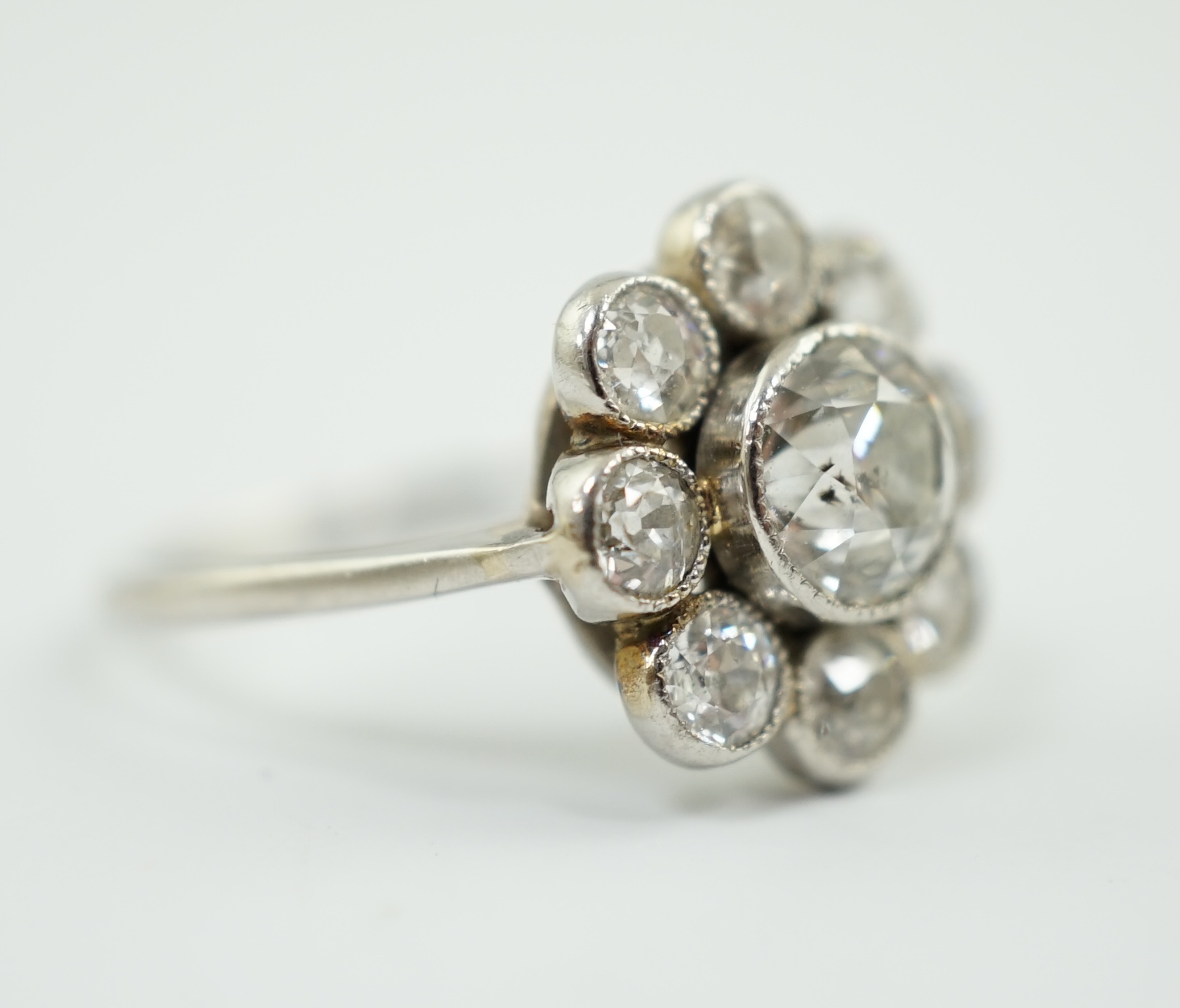 A platinum? and millegrain set nine stone diamond flower head cluster ring